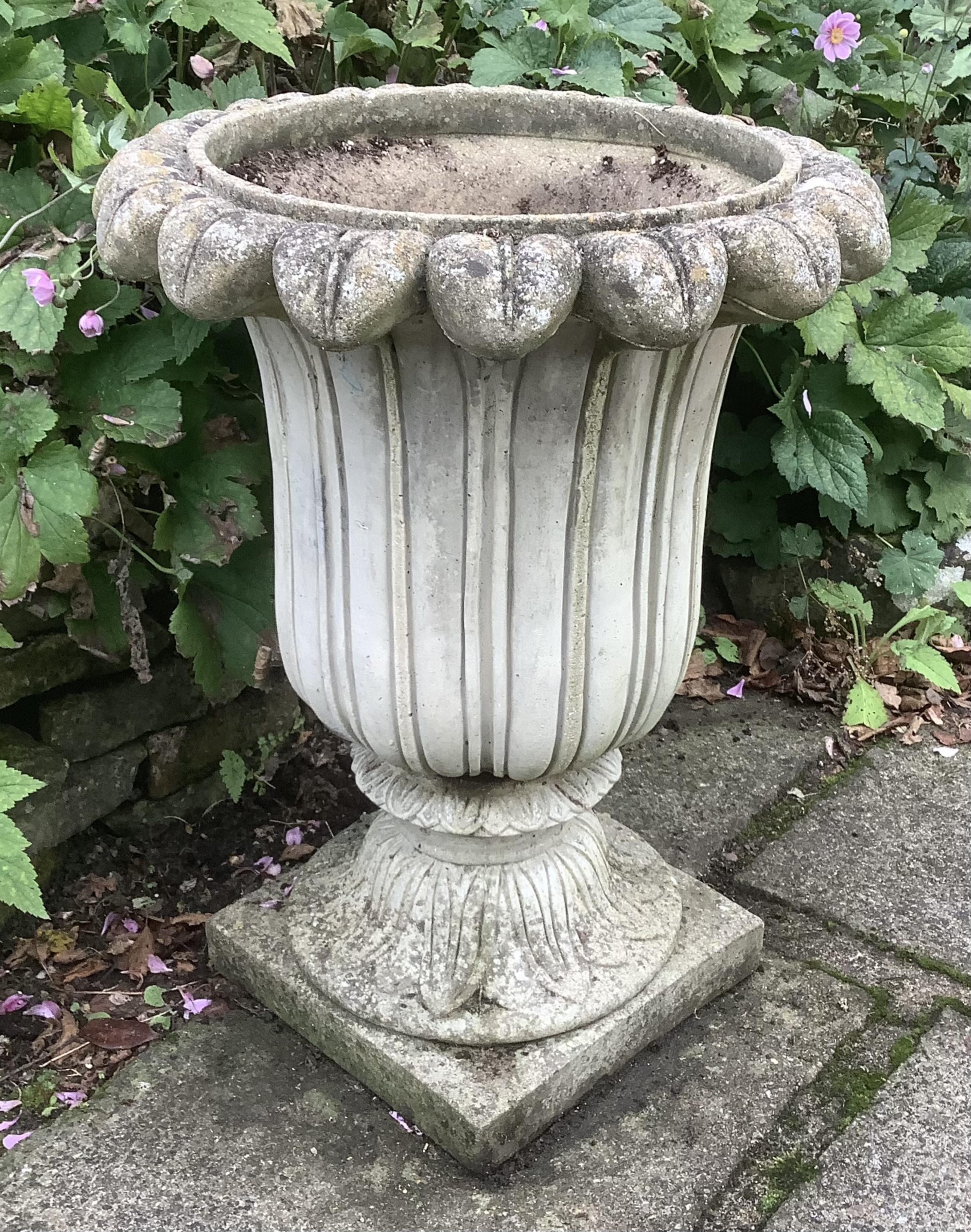 A pair of reconstituted stone tulip urns, height 66cm, depth 50cm, planting removed. Condition - weathered, otherwise good